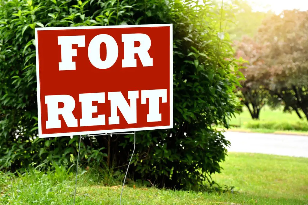 for-rent-sign-in-a-yard-with-grass-and-bushes-hou-2022-11-14-10-34-25-utc